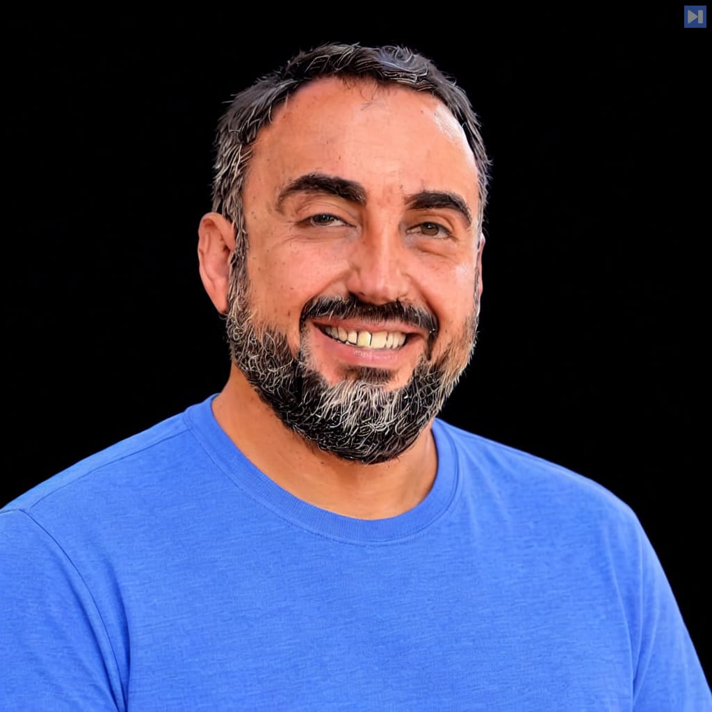 Alex Stamos smiling in a blue T-shirt against a black background.