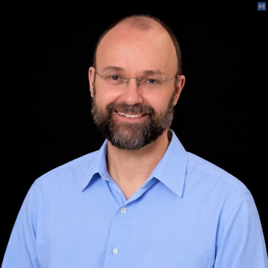 Head-and-shoulders portrait of Andrew McCallum against a black background.