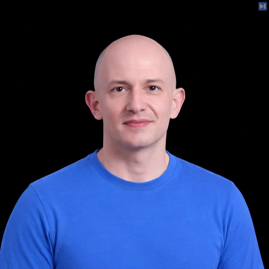 Head-and-shoulders portrait of Greg Pstrucha against a black background.