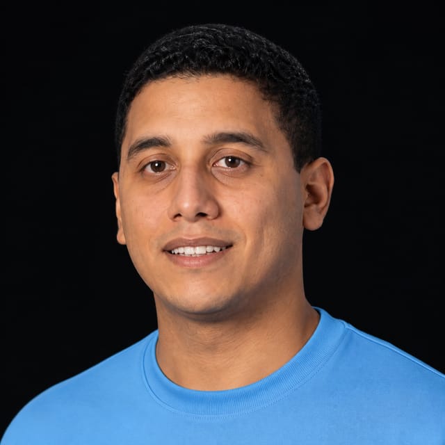 AI-generated portrait of Hassan El Mghari wearing an AI Videos-blue top against a black background.