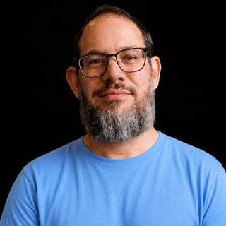 AI-generated portrait of Nate B Jones wearing an AI Videos-blue top against a black background.
