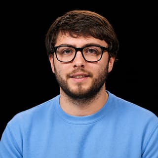 AI-generated portrait of Ryan Greenblatt wearing an AI Videos-blue top against a black background.