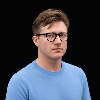 AI-generated portrait of Tim Scarfe wearing an AI Videos-blue top against a black background.