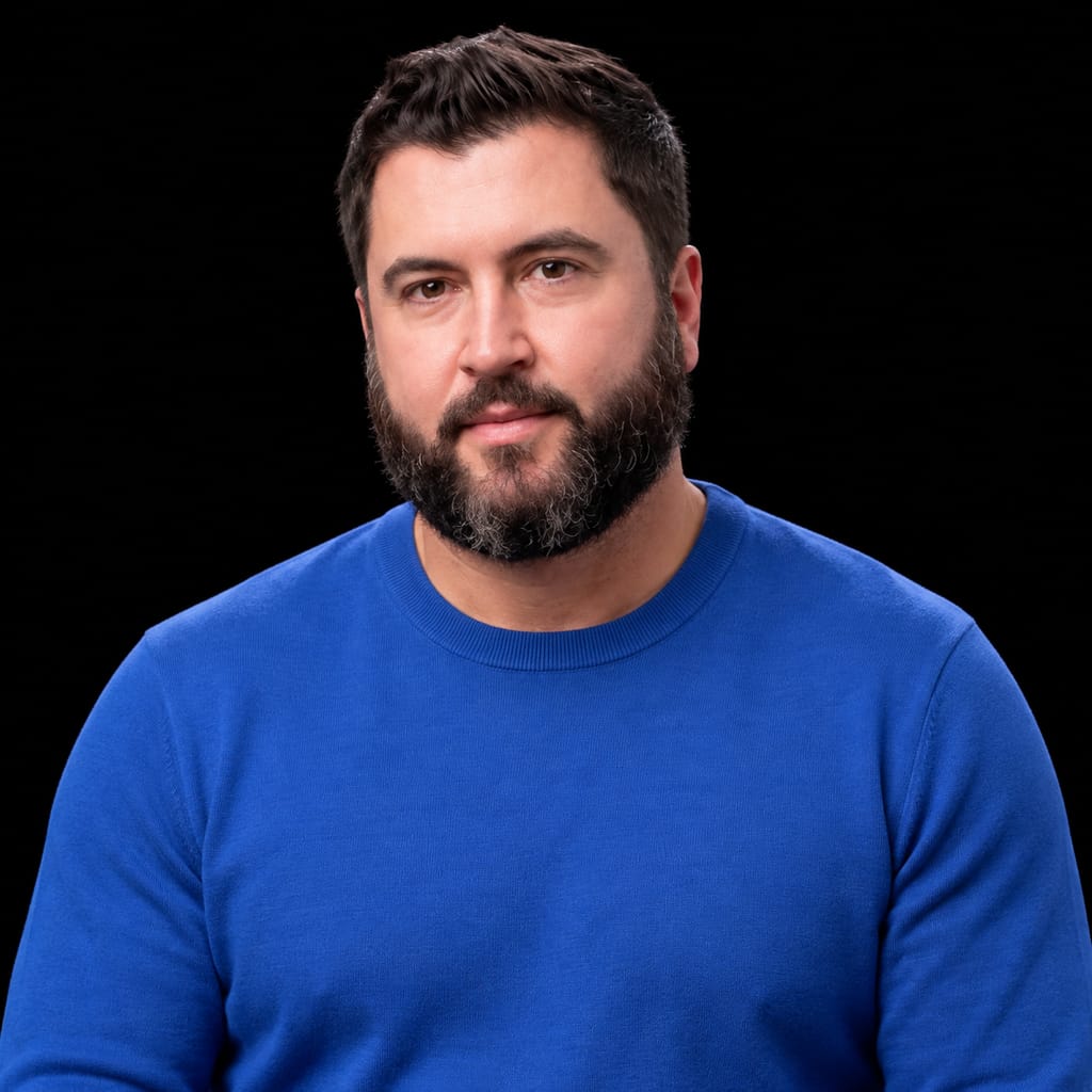 Head-and-shoulders portrait of Travis Fisher against a black background.